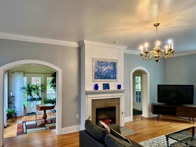 living room with wood-type flooring, a chandelier, and crown molding