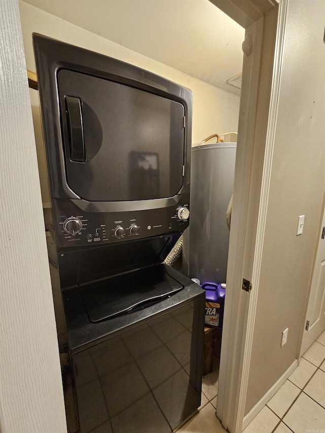 laundry area featuring stacked washer / drying machine and light tile patterned floors