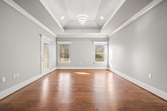 interior space featuring a raised ceiling, ornamental molding, hardwood / wood-style floors, and a chandelier