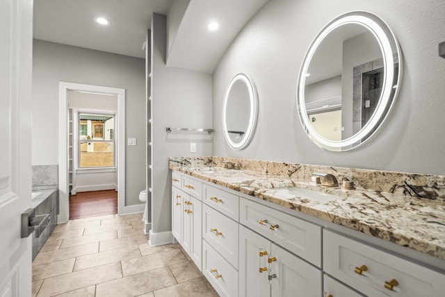 bathroom with a tub to relax in, vanity, and toilet