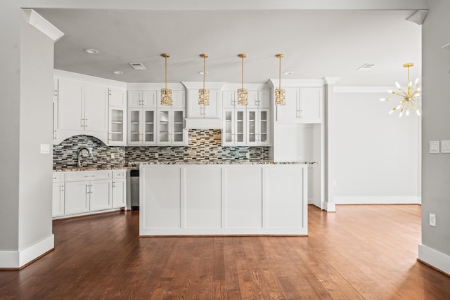 kitchen with decorative light fixtures, a center island, hardwood / wood-style flooring, decorative backsplash, and white cabinets