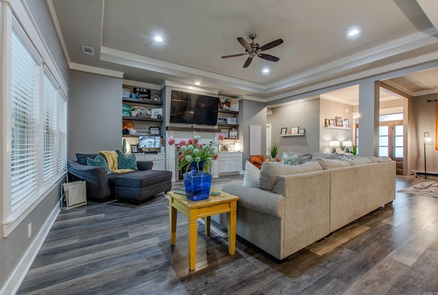 living room featuring dark hardwood / wood-style floors, ornamental molding, a raised ceiling, and ceiling fan