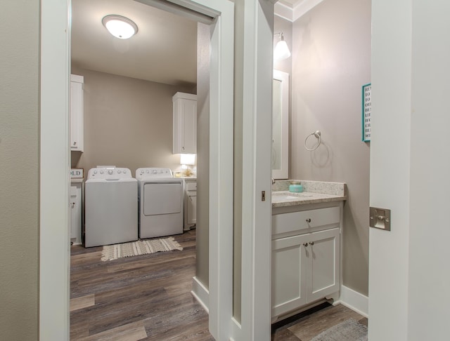 clothes washing area with dark wood-type flooring, washing machine and dryer, and cabinets