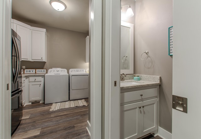 clothes washing area featuring dark hardwood / wood-style flooring, sink, and washer and clothes dryer