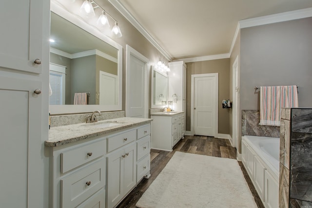 bathroom with ornamental molding, a washtub, hardwood / wood-style floors, and vanity