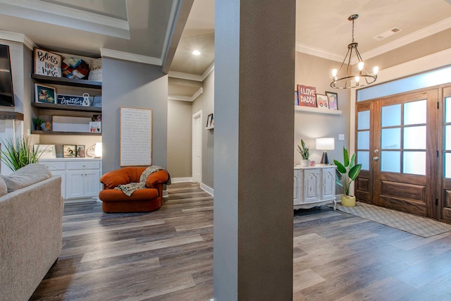 foyer entrance with ornamental molding, dark hardwood / wood-style flooring, and a notable chandelier