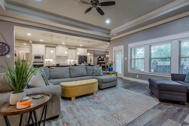 living room featuring ceiling fan, ornamental molding, a tray ceiling, and hardwood / wood-style floors