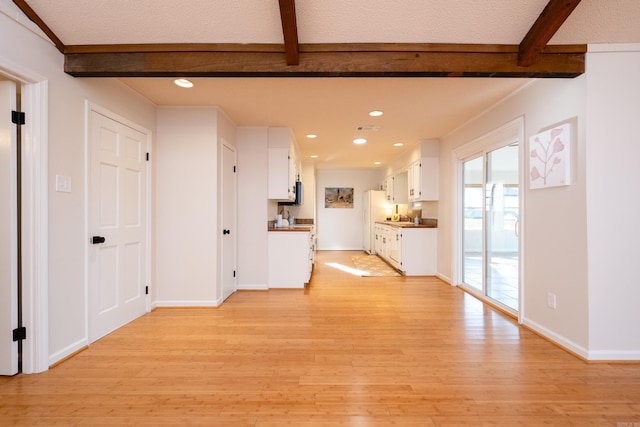 unfurnished living room featuring beam ceiling and light hardwood / wood-style flooring