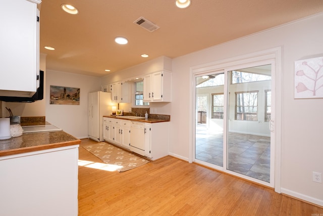 kitchen with white cabinetry, white appliances, sink, and light hardwood / wood-style flooring