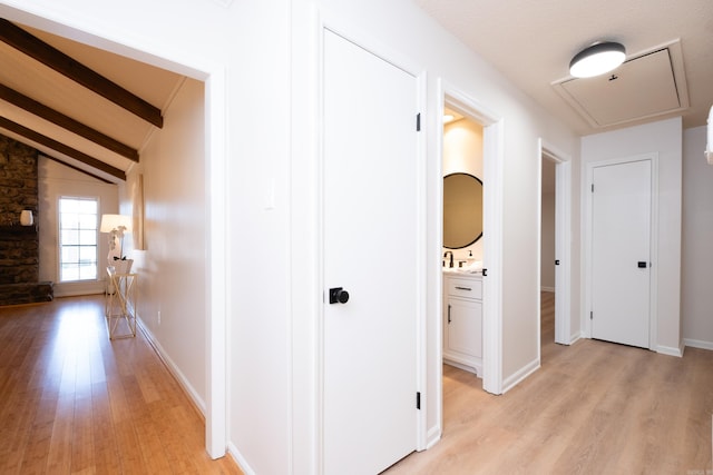 hall featuring light hardwood / wood-style flooring and vaulted ceiling with beams