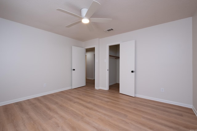 unfurnished bedroom with ceiling fan, a closet, light hardwood / wood-style flooring, and a textured ceiling