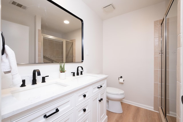 bathroom featuring a shower with door, wood-type flooring, vanity, and toilet