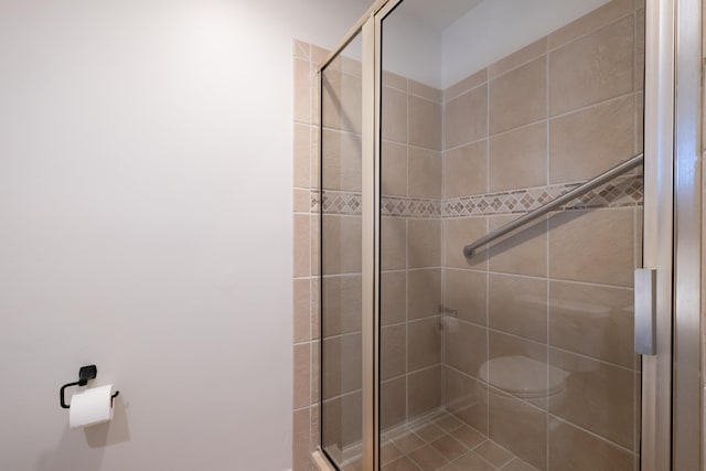 bathroom featuring a shower with shower door and toilet