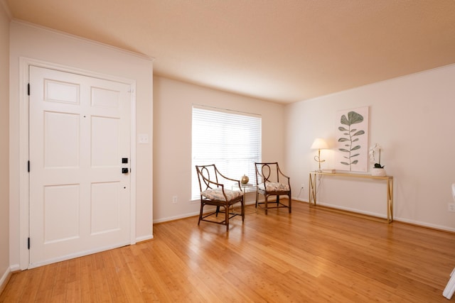 sitting room featuring ornamental molding and light hardwood / wood-style floors