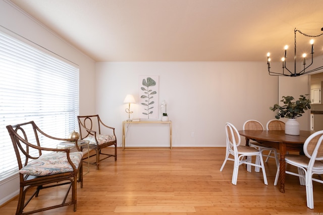 dining area with crown molding, a chandelier, and light hardwood / wood-style flooring