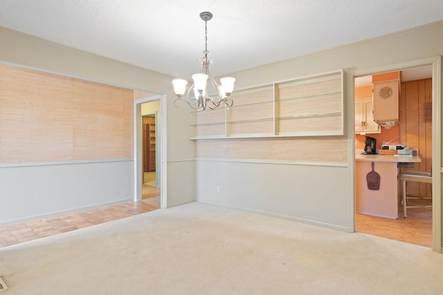 unfurnished dining area featuring a textured ceiling, carpet floors, and a chandelier