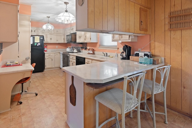 kitchen with sink, a breakfast bar area, black appliances, decorative light fixtures, and kitchen peninsula