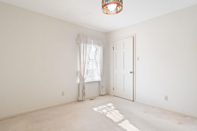 empty room with light colored carpet and a textured ceiling