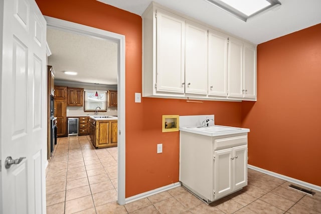 washroom with sink, cabinets, light tile patterned floors, washer hookup, and beverage cooler