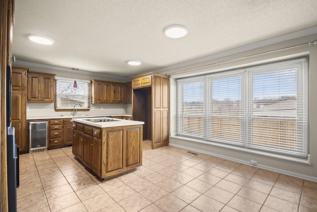 kitchen featuring wine cooler, sink, a center island, hanging light fixtures, and ornamental molding