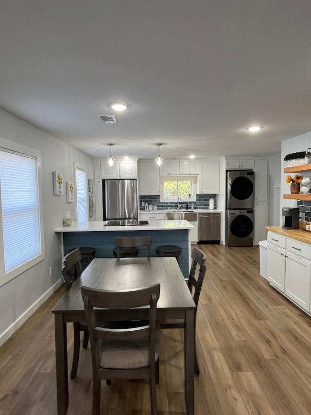 dining space featuring stacked washer / dryer, sink, and light wood-type flooring