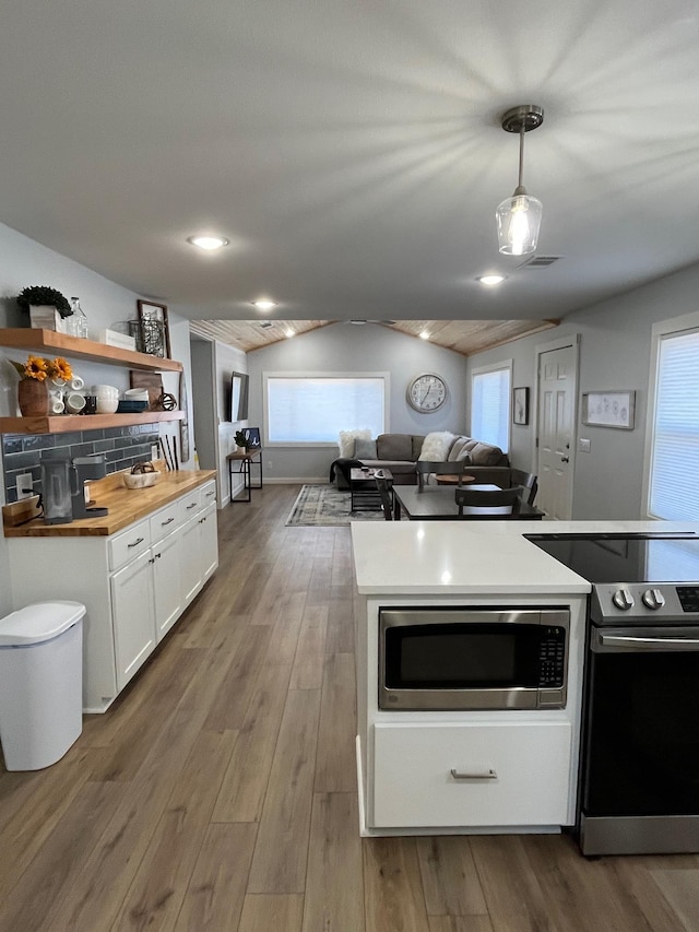 kitchen with white cabinetry, wooden counters, decorative light fixtures, wood-type flooring, and appliances with stainless steel finishes