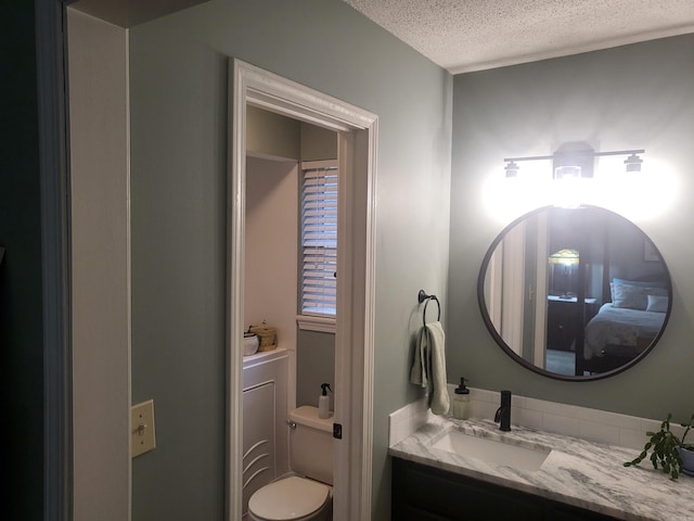 bathroom with vanity, toilet, and a textured ceiling