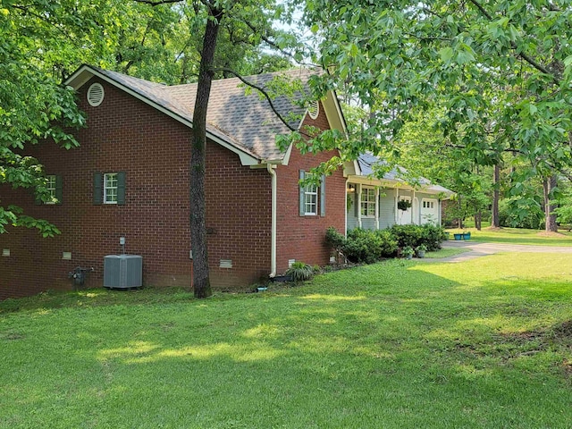 view of side of home featuring central AC and a yard