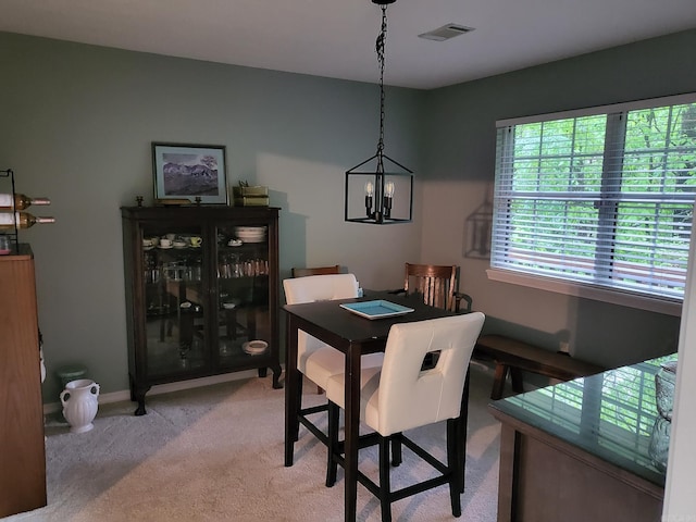 carpeted dining area with a chandelier