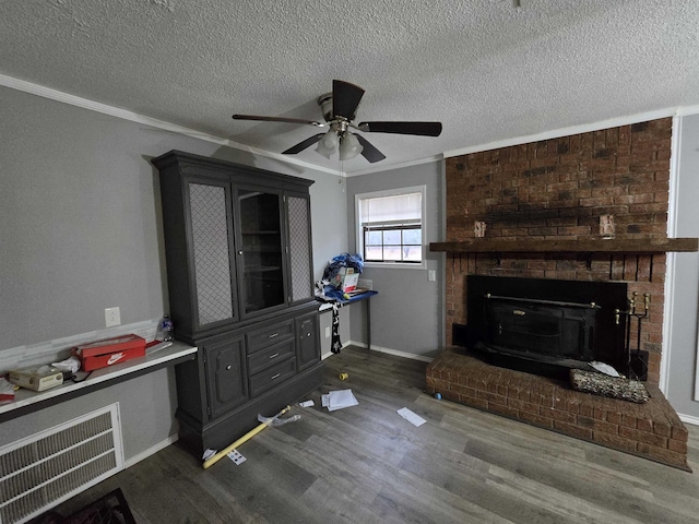 living room with dark hardwood / wood-style flooring, a fireplace, ornamental molding, and a textured ceiling