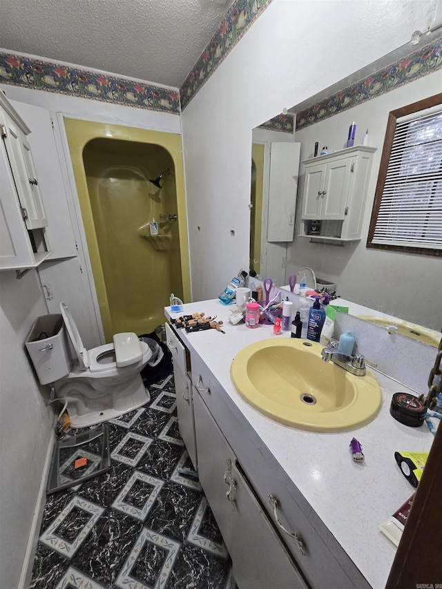 bathroom with vanity, a textured ceiling, toilet, and walk in shower