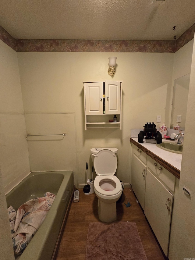 bathroom with vanity, wood-type flooring, a textured ceiling, and a bathtub