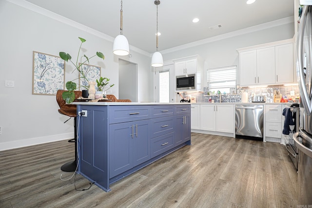 kitchen with appliances with stainless steel finishes, white cabinets, decorative backsplash, hanging light fixtures, and blue cabinetry