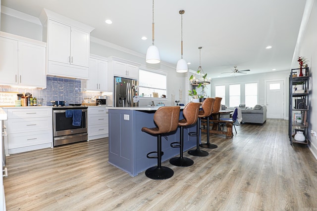 kitchen with pendant lighting, appliances with stainless steel finishes, white cabinetry, a center island, and tasteful backsplash