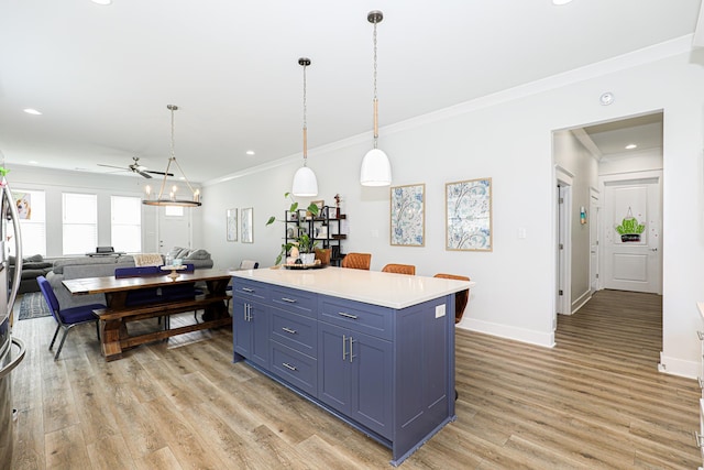 kitchen with a kitchen island, decorative light fixtures, blue cabinets, ornamental molding, and light hardwood / wood-style flooring