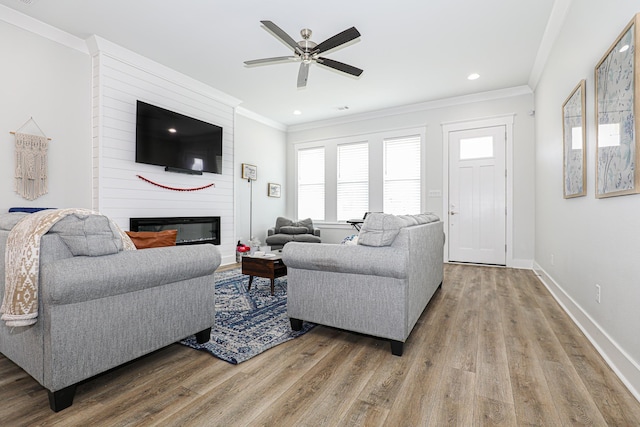 living room with hardwood / wood-style flooring, a fireplace, ornamental molding, and ceiling fan