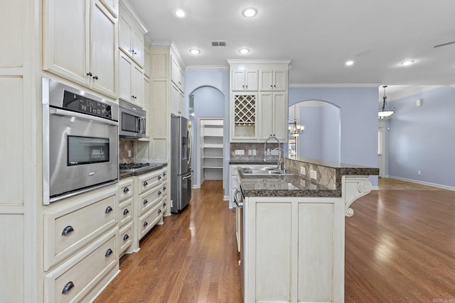 kitchen featuring sink, hanging light fixtures, stainless steel appliances, tasteful backsplash, and ornamental molding