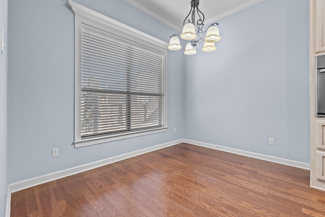 spare room featuring a notable chandelier, crown molding, and wood-type flooring