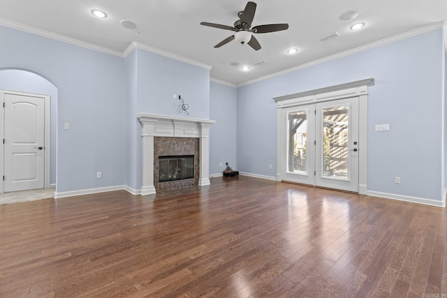 unfurnished living room featuring a premium fireplace, dark hardwood / wood-style floors, ceiling fan, and crown molding