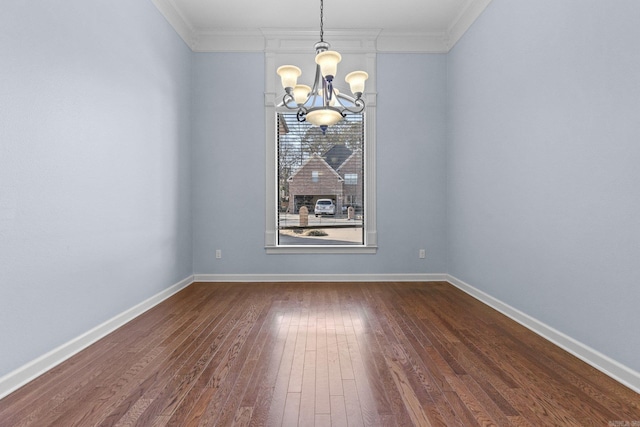 spare room featuring ornamental molding, dark wood-type flooring, and a chandelier