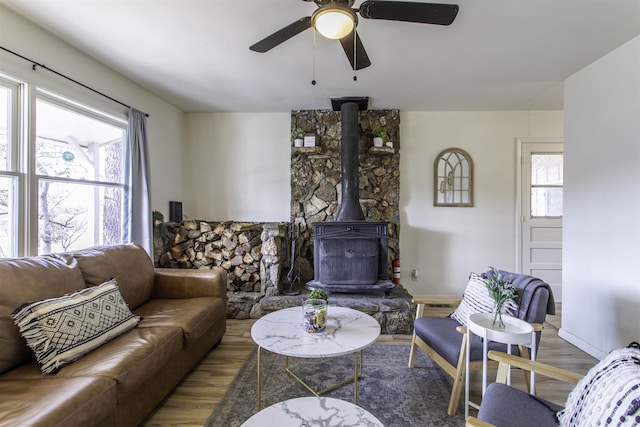 living room with hardwood / wood-style floors, ceiling fan, and a wood stove