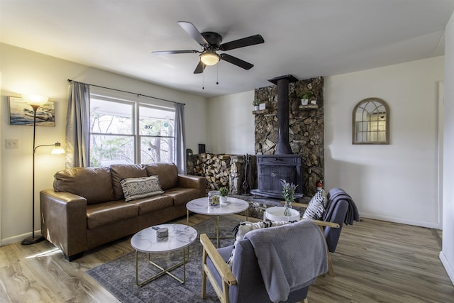 living room with hardwood / wood-style flooring, a wood stove, and ceiling fan