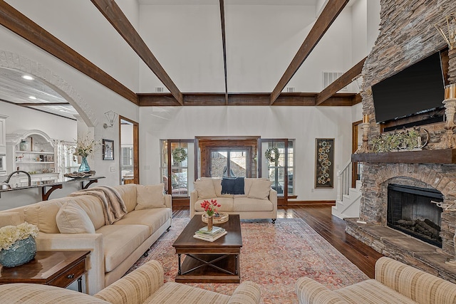 living room with a stone fireplace, hardwood / wood-style floors, a high ceiling, and a wealth of natural light