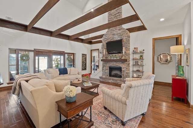 living room featuring a stone fireplace, dark wood-type flooring, beam ceiling, and a towering ceiling