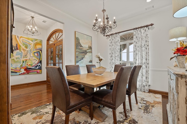 dining space with french doors, ornamental molding, a chandelier, and light hardwood / wood-style floors