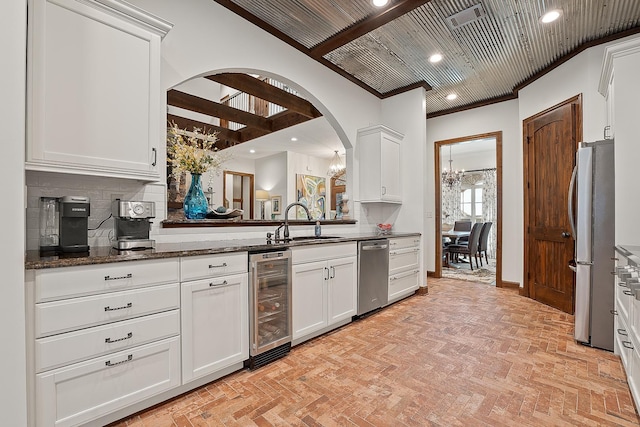 kitchen with wine cooler, sink, crown molding, and white cabinets