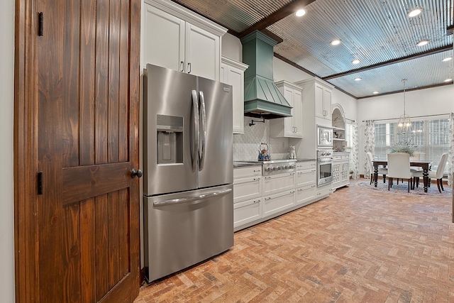 kitchen with custom exhaust hood, white cabinetry, appliances with stainless steel finishes, pendant lighting, and backsplash