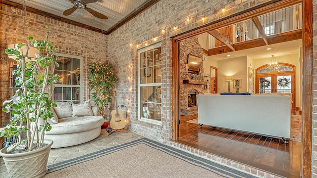 interior space featuring french doors, a stone fireplace, and ceiling fan with notable chandelier