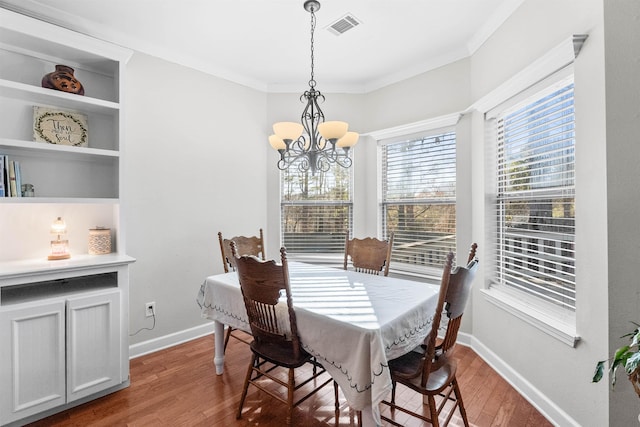 dining space featuring crown molding, dark hardwood / wood-style floors, a notable chandelier, and built in features