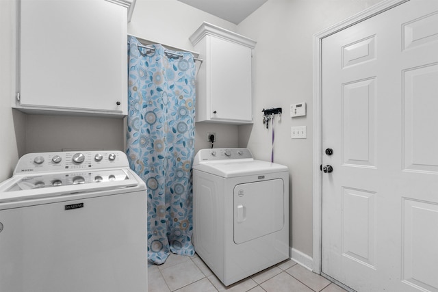 clothes washing area with light tile patterned floors, washer and clothes dryer, and cabinets